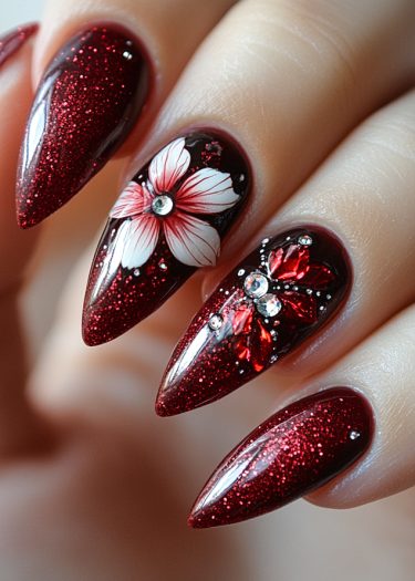 Glamorous glittery red stiletto nails with floral designs and rhinestones for a luxurious look.