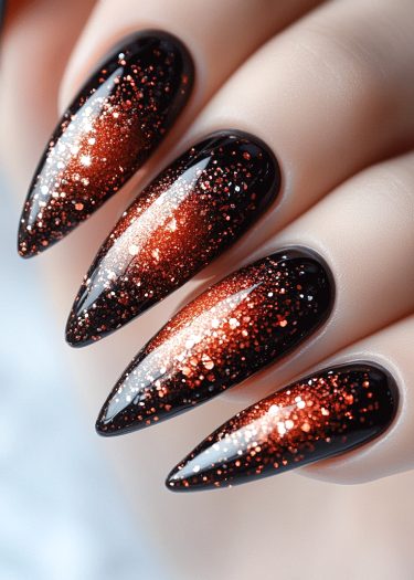 Stiletto nails featuring glossy black polish and shimmering copper glitter for a bold look.