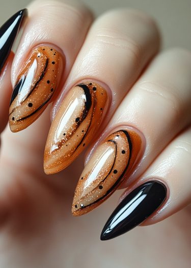 Elegant stiletto nails with orange glitter and chic black accents for bold nail art.