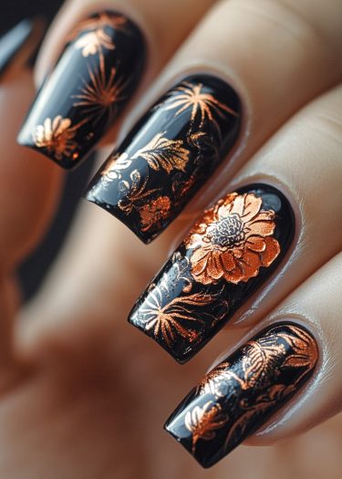 Glossy black floral nail art with metallic copper designs for a stylish, elegant look.