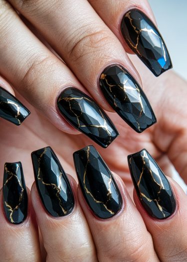 Elegant glossy black nails with gold marble patterns showcase luxurious, artistic manicure design.