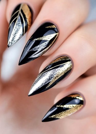 Expertly manicured glossy black stiletto nails with luxurious metallic gold and silver designs.