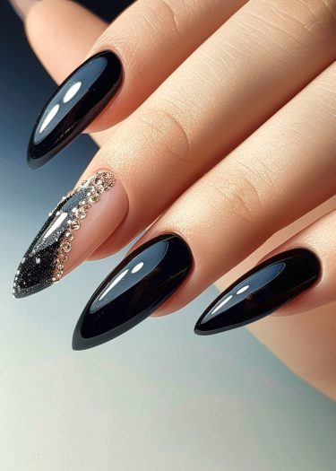 Elegant almond-shaped glossy black nail art with glitter and rhinestones for a glamorous look.