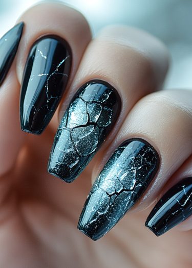 Stiletto nails with glossy black shattered glass design demonstrate bold, modern nail art.