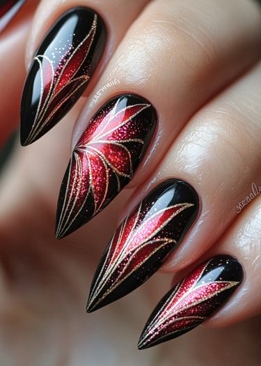 Stunning stiletto nails featuring glossy black base, red glitter gradient, and elegant gold accents.