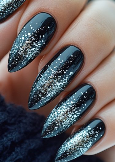 Glamorous black stiletto nails with sparkling silver and gold glitter gradient for a stunning manicure.