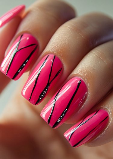 Elegant glossy pink nail art with intricate black designs and silver accents.