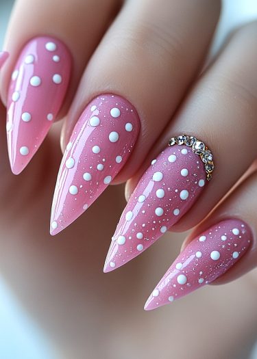 Glossy pink stiletto nails with playful polka dots and sparkling rhinestones for stylish elegance.