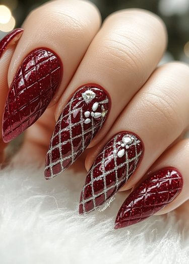 Elegant glossy red nail art with quilted design and sparkling embellishments for a luxurious look.