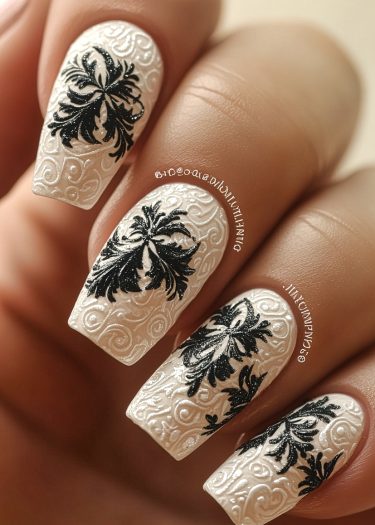 Elegant glossy white nail art with black floral designs and intricate embossed patterns.