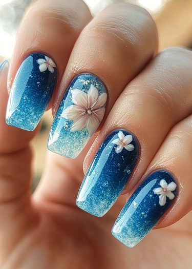 Elegant gradient blue floral nails with glitter and gems for a stunning manicure design.