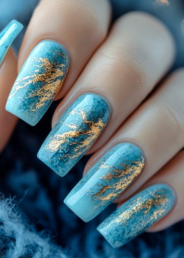 Coffin-shaped ocean blue nails with shimmering gold marble art for elegant nail designs.