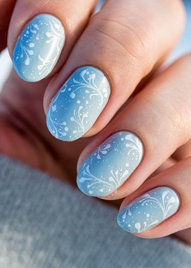 Elegant gradient blue nails with intricate floral design, perfect for a wintery aesthetic.