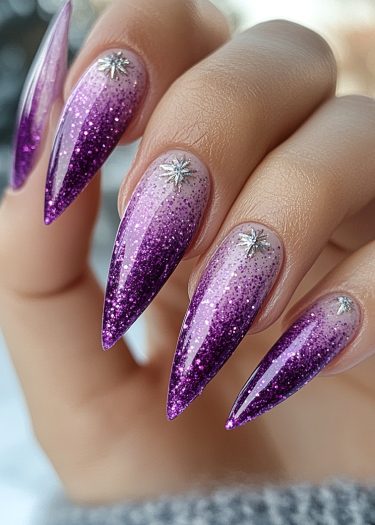 Elegant gradient glitter nails with metallic embellishments in purple and lavender hues.