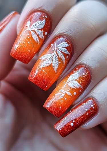 Exquisite sunset gradient nail art with white leaf designs and glossy finish for elegant style.