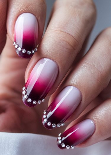 Elegant gradient ombre nails in pink to burgundy with rhinestone accents showcase luxurious nail art.