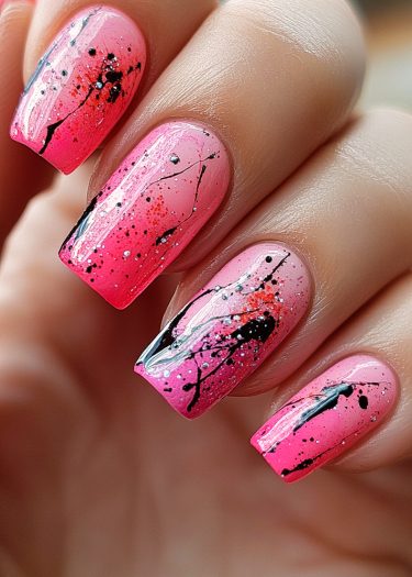 Vibrant gradient pink nail art with black and silver splatter design for a playful look.