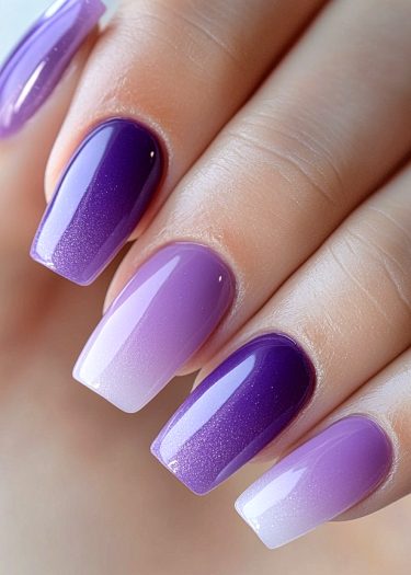 Elegant gradient purple nail art with glossy ombre effect in a sophisticated squoval shape.