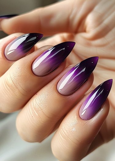 Elegant stiletto nails with a stunning violet ombre effect and glossy finish.