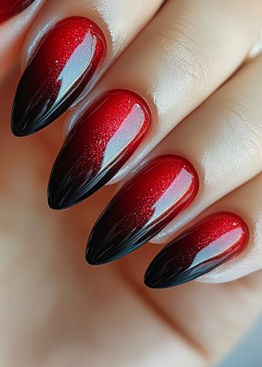 Vibrant red to black ombre stiletto nail art with glitter for a glamorous, bold look.