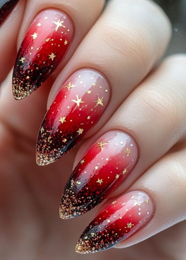 Stiletto nails feature a stunning black-to-red gradient with gold star decals and glitter.