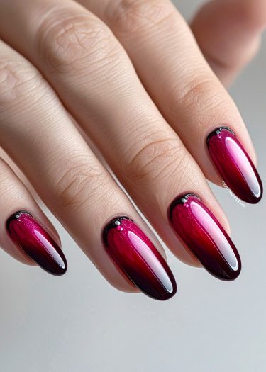 Elegant ombre manicure in burgundy and pink with decorative embellishments on stylish nails.