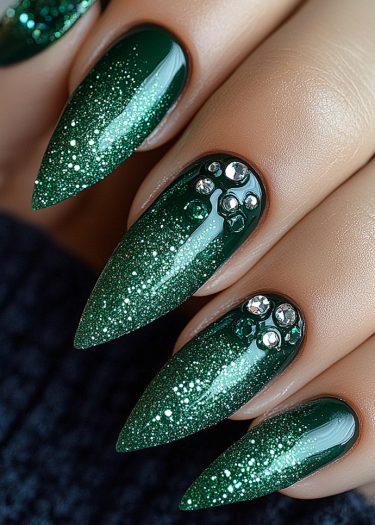 Elegant almond-shaped green nails with glitter and rhinestones for a sophisticated manicure.