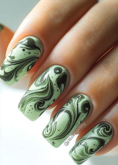 Elegant green marble nail art with intricate swirls and glossy finish on well-manicured nails.