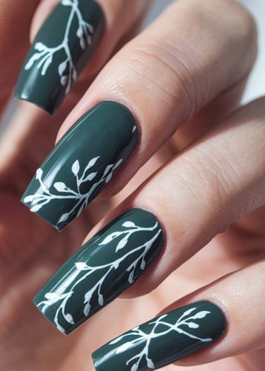 Elegant green nail art with intricate white designs on long, manicured square-tip nails.