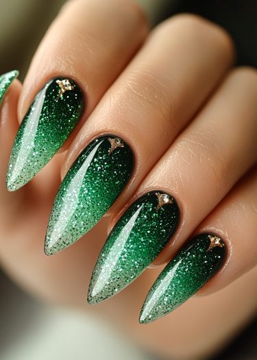 Elegant green ombre glitter nails with rhinestones on stylish stiletto shapes.