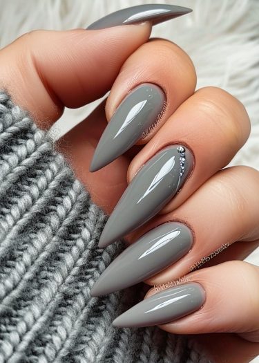 Stiletto gray nails with rhinestones, elegant manicure paired with a cozy knit sweater.