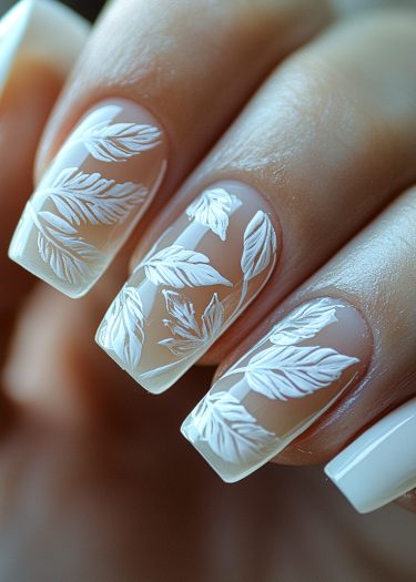 Elegant nail art featuring intricate white leaf patterns on a nude base.