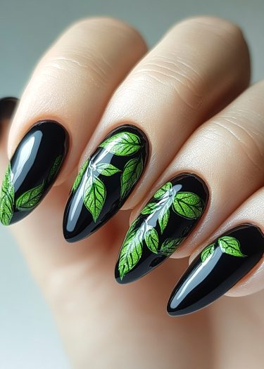 Elegant black nail art featuring intricate green leaf designs for sophisticated manicures.