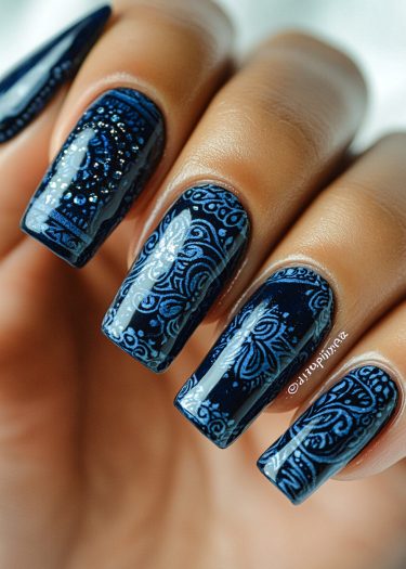 Elegant navy blue nail art featuring intricate light blue designs for a luxurious manicure.