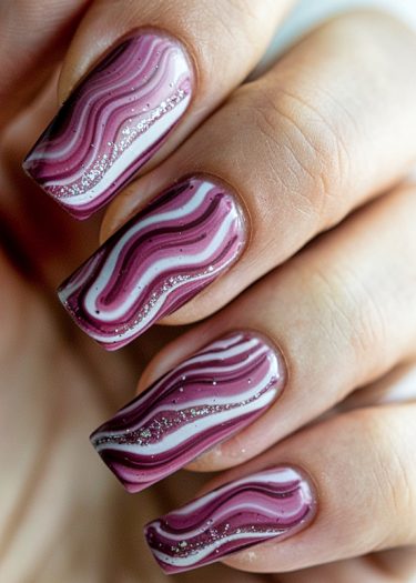 Elegant marbled nail art in pink and white with glitter, showcasing intricate nail design.