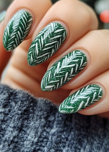 Elegant almond-shaped nails with glittery green polish and intricate white herringbone nail art.