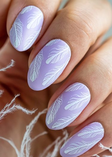 Elegant lavender nail art featuring delicate white feather designs and soft textures.