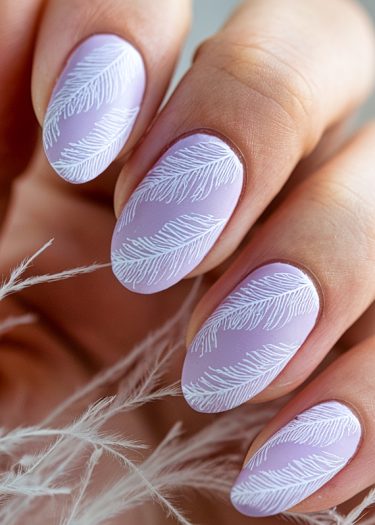 Pastel lavender nail art with intricate white feather designs for a chic, elegant look.