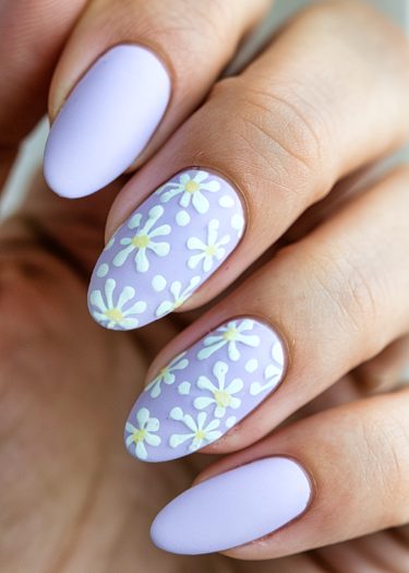 Elegant lavender floral manicure featuring detailed daisies on long almond-shaped nails.