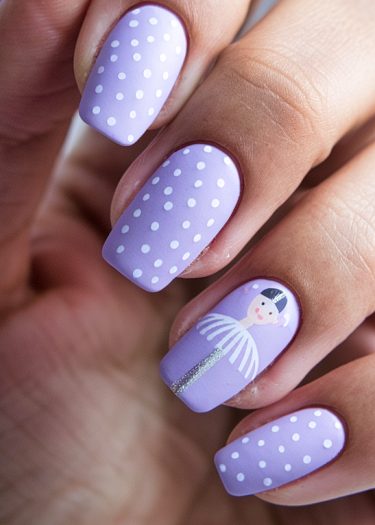 Lavender manicure with polka dots and a ballerina illustration on elegant, well-groomed nails.