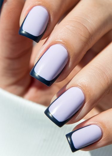 Sophisticated lilac nails with navy blue tips, showcasing modern French manicure style.