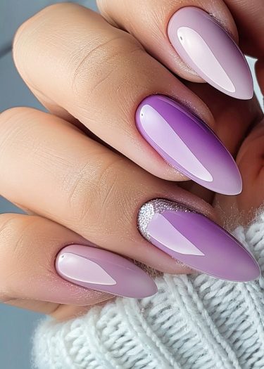 Elegant lavender-pink ombre nails with almond shape and glitter accents for a sophisticated look.