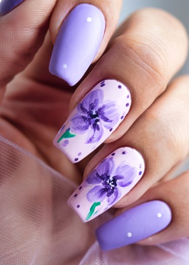 Sophisticated purple nail art with floral designs and pastel polish for elegant manicured nails.