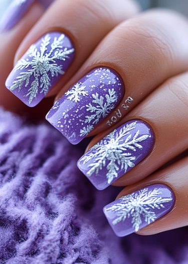 Lavender nails with silver snowflakes create a festive winter manicure look.