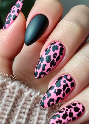 Stylish leopard print manicure with pink and black design on elegantly shaped almond nails.