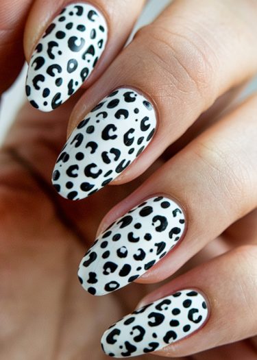 Stunning leopard print nail art on almond-shaped nails with a glossy white base coat.