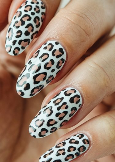 Stunning leopard print nail design on almond-shaped white nails, showcasing professional manicure art.