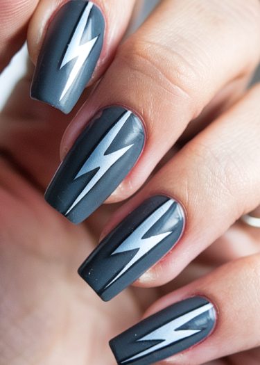 Bold lightning bolt nail art on matte gray nails for a striking manicure.