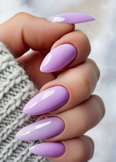 Elegant lavender stiletto nails with silver glitter, wrapped in cozy gray knit fabric.