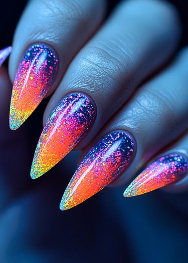 Stunning long stiletto nails showcase vibrant blue to yellow ombre with glitter details.